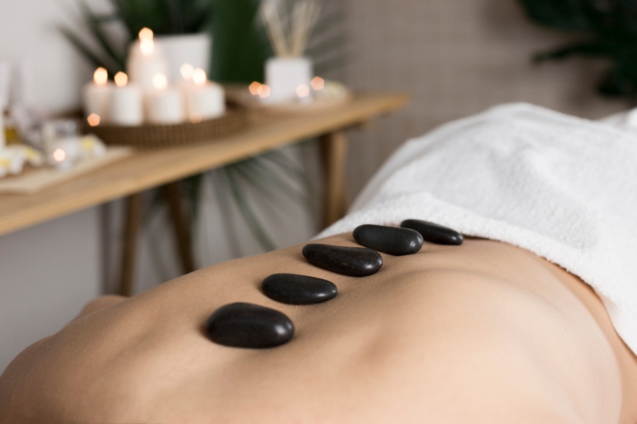Hot stone massage therapy with heated stones placed on the back for deep relaxation and stress relief